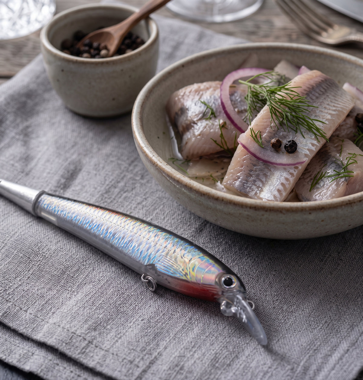 Plockgaffeln Sillen bredvid ett fat inlagd sill med rödlök och dill – miljöbild